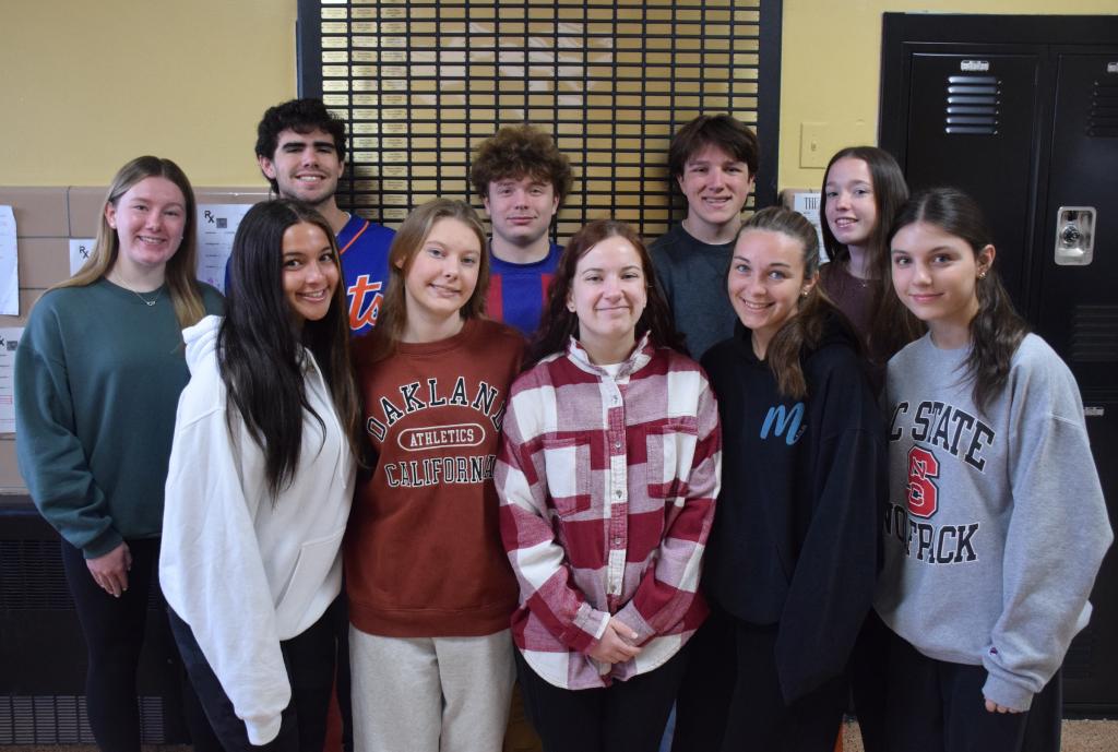 group of teens standing in front of a wall plaque